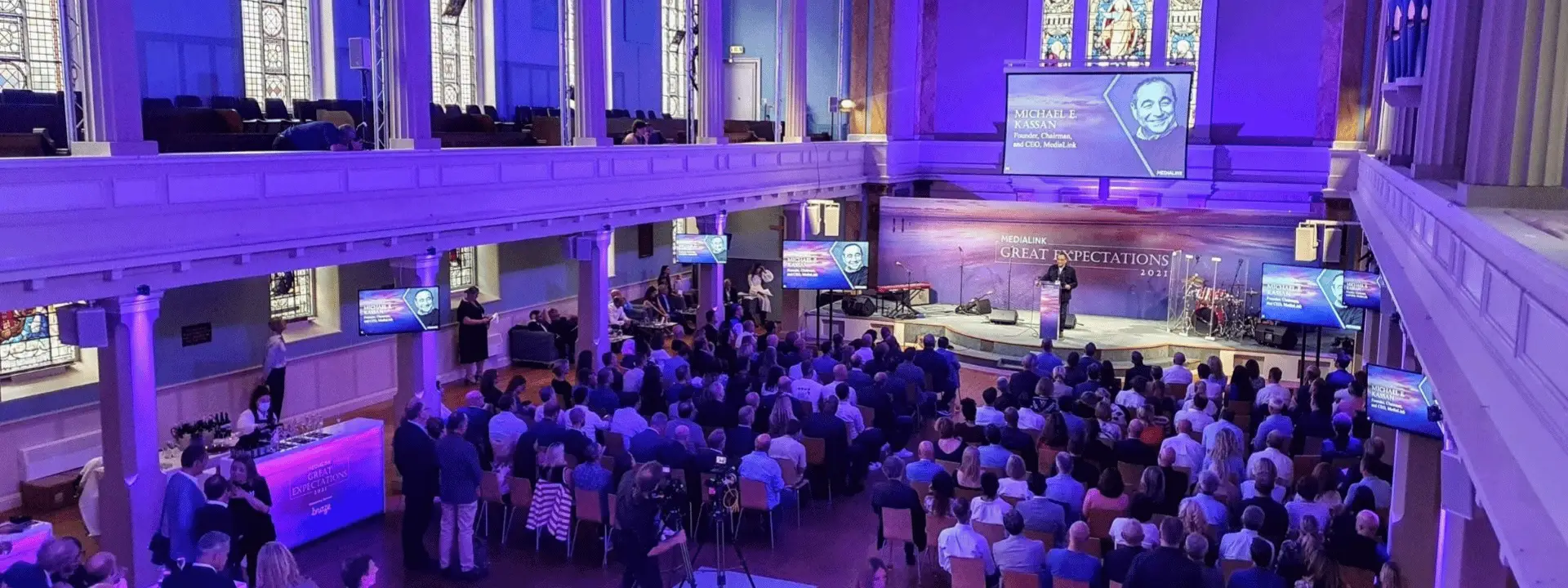 Church building used as an event venue with seated guests, stage, screens and professional event production.