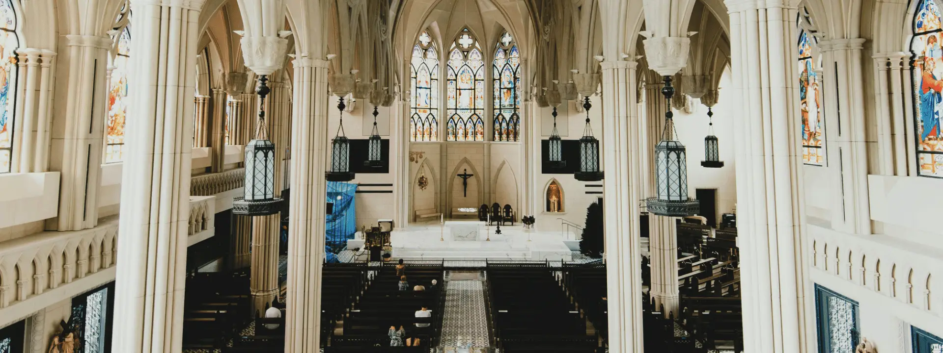 Church interior with altar, crucifix, stained glass and people seated in the pews Why: This places worship and people together, reinforcing the argument that the sacred purpose of the building is ultimately connected to what happens within it.